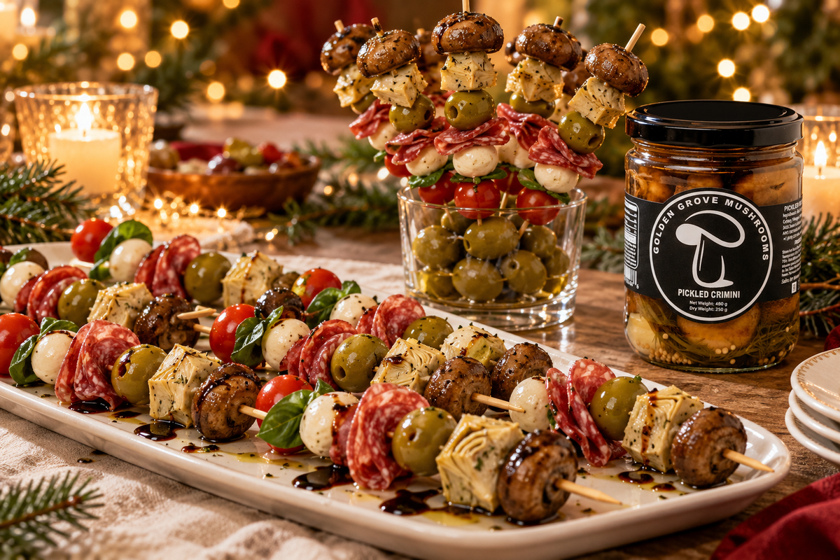 Antipasto skewers with mozzarella, tomato, basil, salami, olive and a pickled crimini mushroom on a party table, beside a jar of pickled crimini