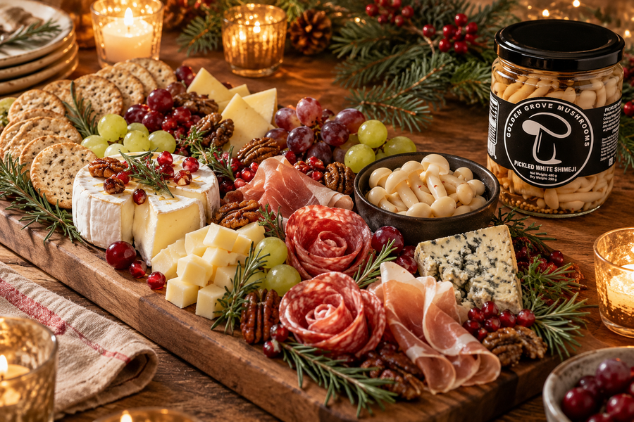 A long Christmas charcuterie board with cheeses, salami, grapes, pomegranate, rosemary and a bowl of pickled white shimeji