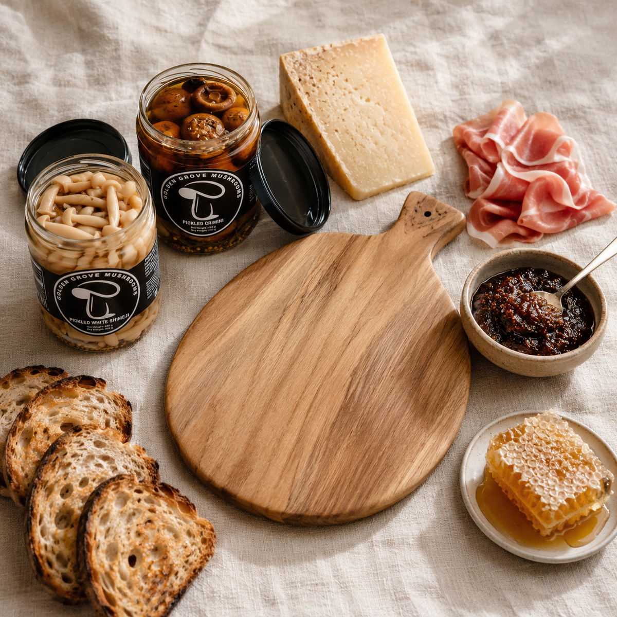 Cheese, prosciutto, fig jam and two jars of pickled mushrooms gathered before assembly