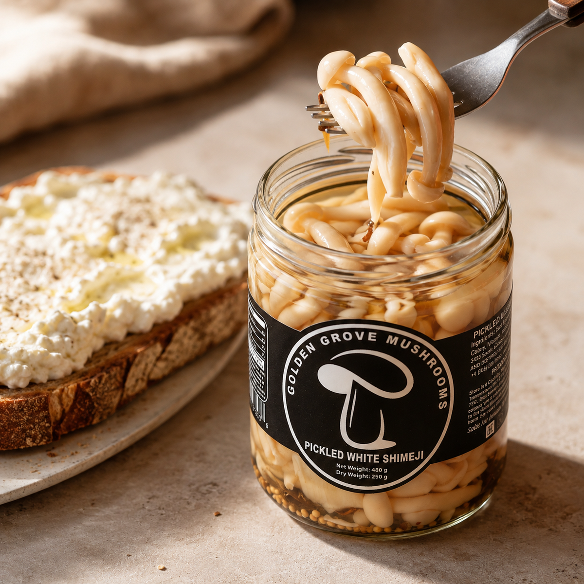 A fork lifting a cluster of pickled white shimeji above a slice of ricotta toast