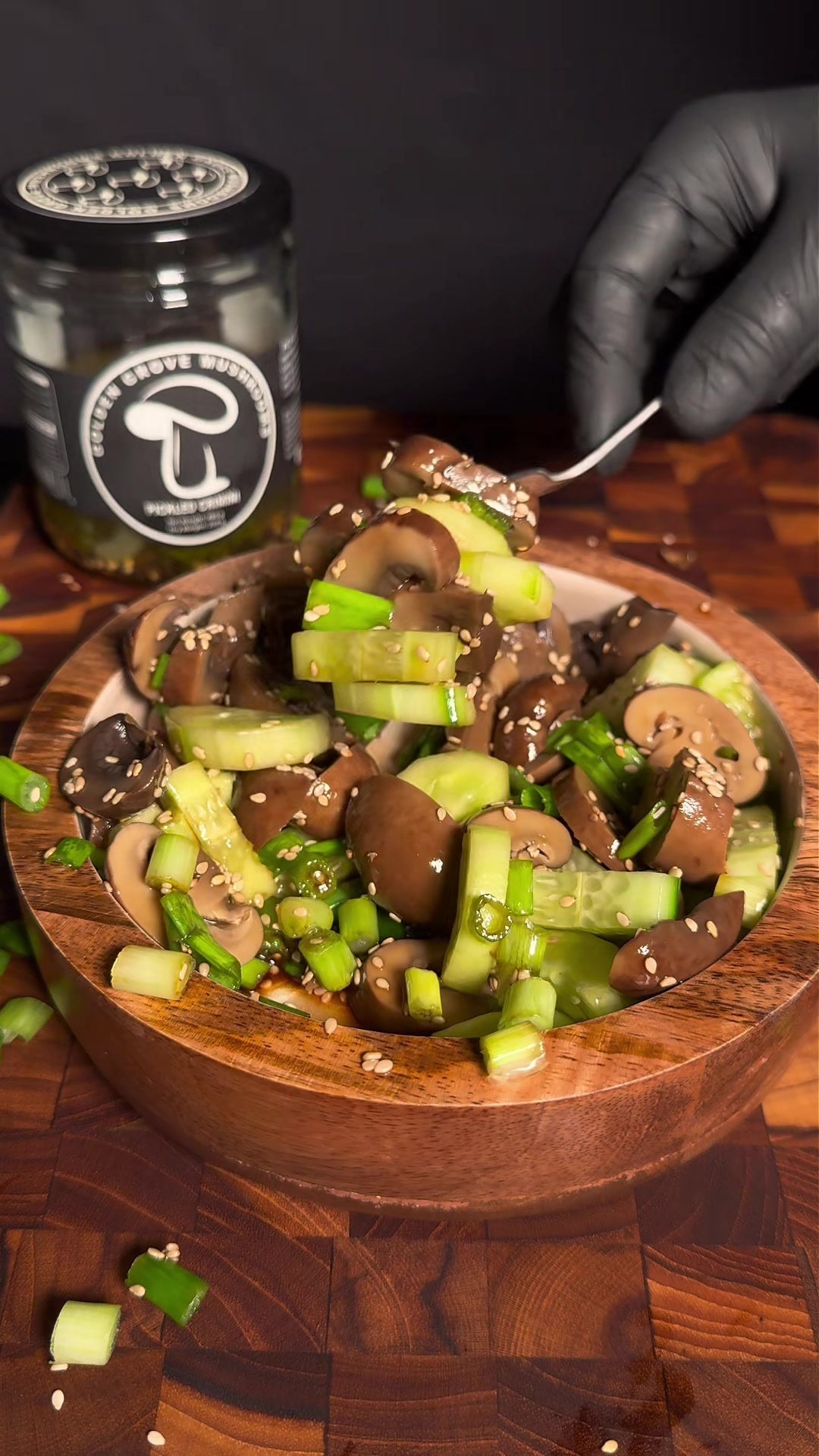 Pickled crimini and cucumber salad with green onion and sesame in a wooden bowl